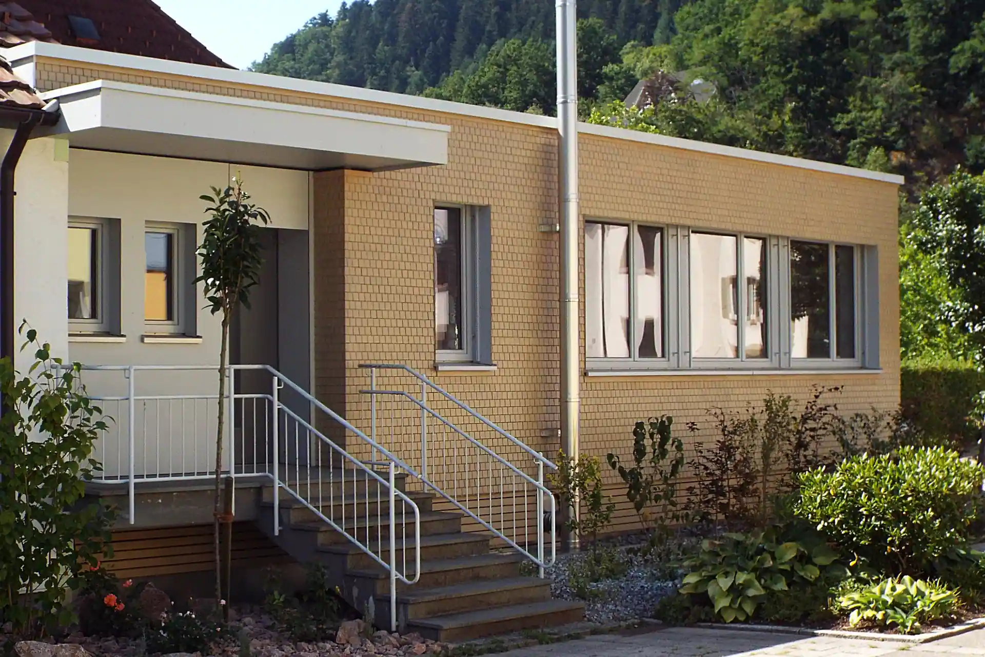 Eingangsportal eines modernen Bungalows mit einer Fassade aus Holzschindeln