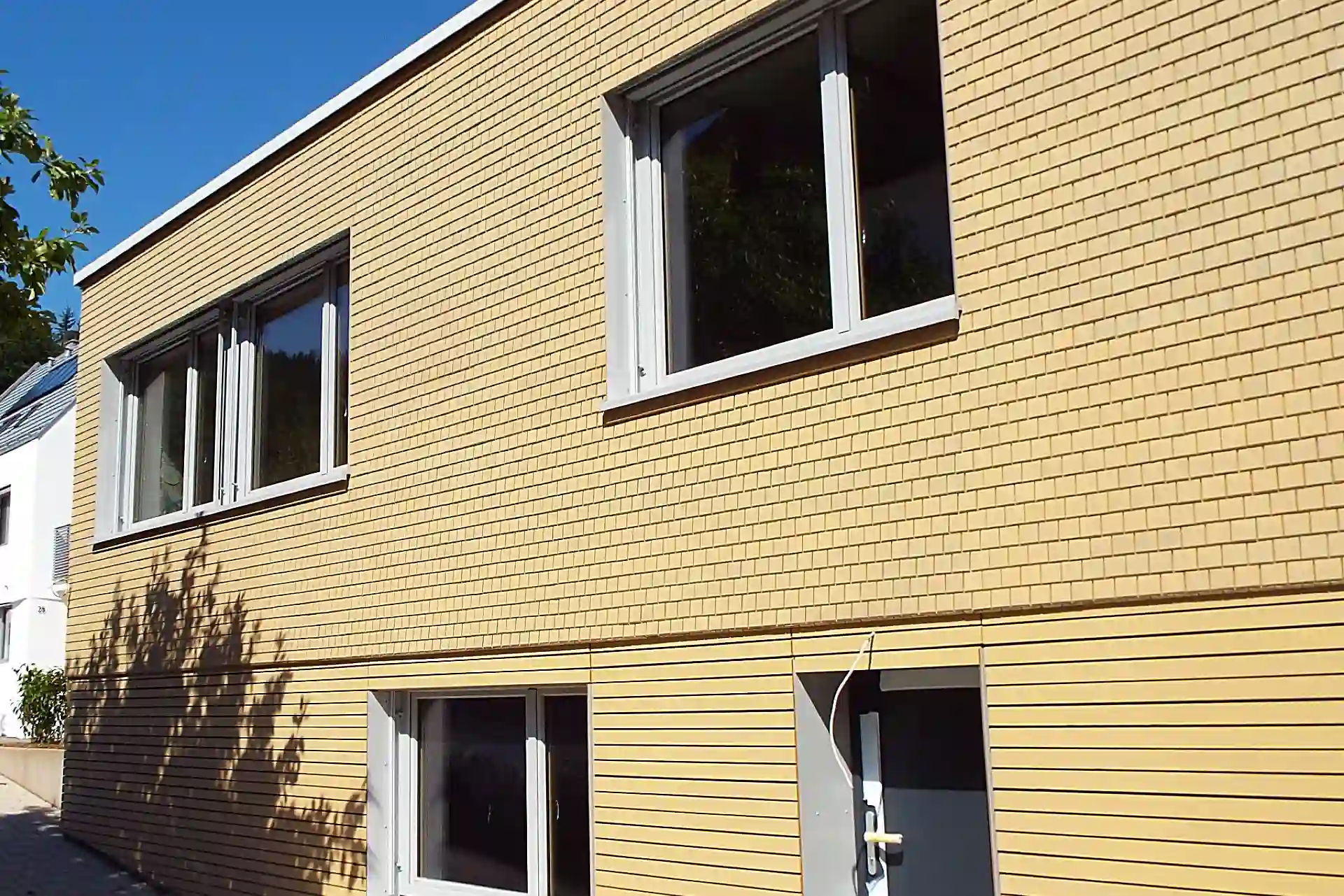 Hell lasiert gestrichene Holzschindelfassade aus Fichte